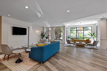 A living room with a blue couch and a television on the wall.